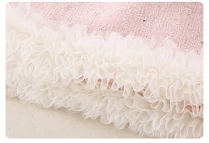 Detalle de tela de tweed rosa con lentejuelas y volantes de encaje crema para niñas