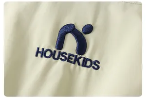 Dettaglio del ricamo HOUSEKIDS sulla giacca con cappuccio color kaki per bambini