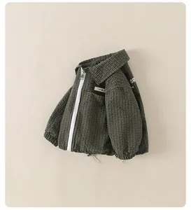 Detailed view of kids dark green plaid jacket featuring white zipper and M patch