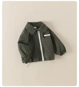 Detail of dark green checkered kids jacket fabric with leather M patch and zipper