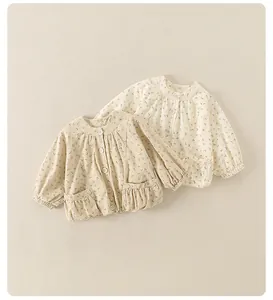 Detail of floral baby jackets in cream and apricot featuring button closures and pockets