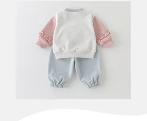 Detailansicht eines Baby-Trainingsanzugs mit rosa Rüschenärmeln und Jogginghose
