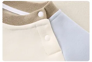 Détail du pull en coton pour bébé avec col contrasté et boutons-pression sur l'épaule