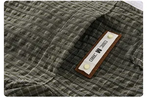 Macro view of olive green plaid fabric texture and leather patch detail on jacket