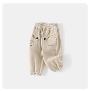 Détail du pantalon beige enfant avec taille élastique, poche ours et poignets côtelés