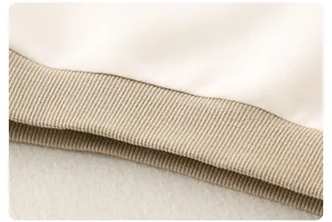 Détail d'un haut en tricot pour bébé blanc avec ourlet côtelé kaki et coutures soignées