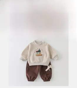 Détail à plat du sweat-shirt beige pour bébé avec broderie maison et pantalon de jogging