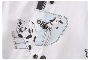 Dettaglio camicia in cotone con motivi a cucciolo disegnati a mano e bottoni in stile legno