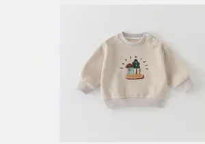 Détail d'un sweat-shirt bébé beige avec boutons à l'épaule et broderie cartoon