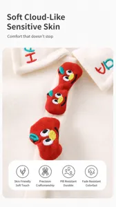Detail of white knit baby sweater featuring colorful HAPPY embroidery and cute patches