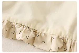 Close-up of floral ruffle hem on a cream cotton jacket for toddler girls