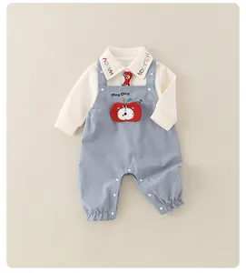 Détail d'un ensemble bébé en coton avec col brodé et joli motif de pomme 3D sur salopette