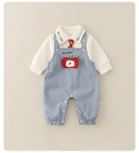 Détail d'une barboteuse bébé avec col brodé et motif horloge pomme sur tissu doux