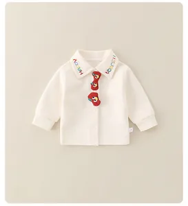 Détail d'un sweat pour bébé crème avec écussons de dessins animés et broderie Happy
