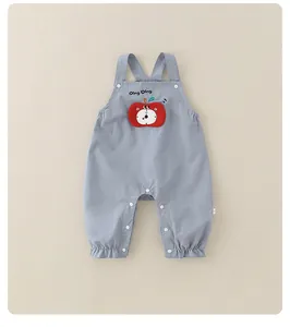 Détail de la salopette bébé bleu clair avec écusson pomme et boutons-pression