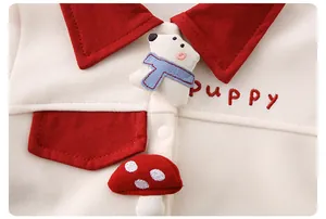 Detail eines Baby-Baumwollsets mit Bären- und Pilzflicken sowie Welpenbestickung