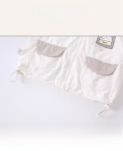 Detail of white toddler jacket with cartoon bear print and striped patch pockets