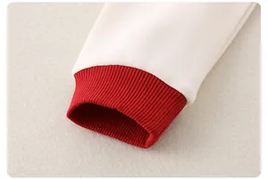 Detail der roten Rippbündchen an creme-weißen Baumwoll-Babyshirts mit hochwertiger Naht