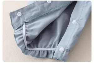 Détail d'une salopette bébé avec boutons-pression et poignets élastiques bleu clair
