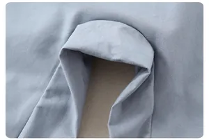 Vue macro de la texture en sergé fin et des coutures soignées sur la salopette enfant