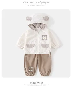 Toddler boy outfit with bear ear hooded jacket and khaki pants set on plain background
