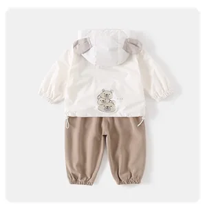 Detail of baby hooded jacket with cute bear print and matching brown trousers set