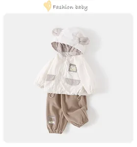 Detail of hooded baby jacket with bear patch and matching brown trousers set