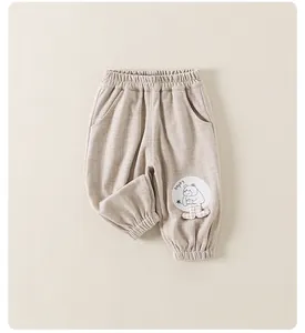 Close-up of baby beige casual pants with striped texture and cartoon bear patch
