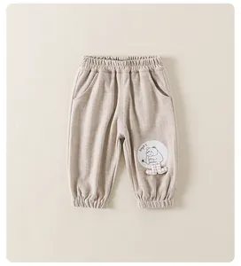 Detail of beige ribbed toddler pants featuring elastic waist and cute cartoon bear patch