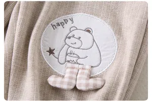 Detail of baby beige knit pants featuring a cute bear patch and happy embroidery