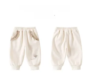 Dettaglio dei pantaloni in cotone per neonata con ricamo a fungo e tasche con volant