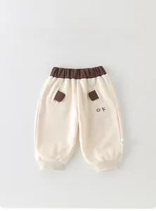 Détail du jogging pour bébé avec taille élastique et broderie OK sur tissu crème