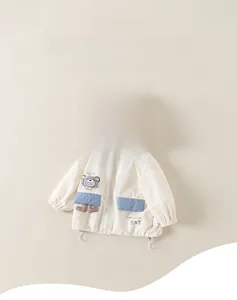 Detail of children's hooded jacket featuring grey plaid lining and cartoon bear patch