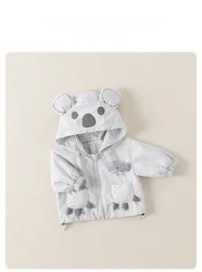 Detail of baby hooded windbreaker featuring koala design and grey plaid inner lining