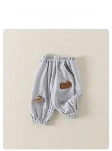 Close-up of grey toddler jogging pants featuring waffle texture and cute dinosaur embroidery