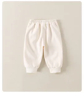 Dettaglio della vita elastica e dei polsini a coste sui pantaloni jogger color crema