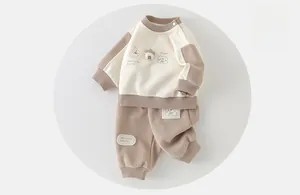 Detail of baby cotton tracksuit showing shoulder snaps and cartoon embroidery textures