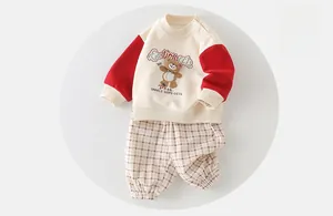 Detail of baby boy cotton outfit featuring bear embroidery and plaid jogger pants
