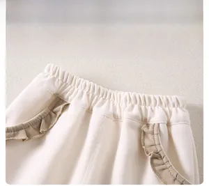 Dettaglio dell'elastico in vita e tasche con volant kaki su pantaloni per neonata