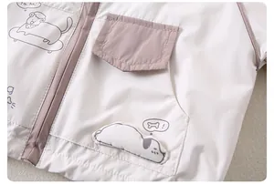 Détail de veste enfant avec broderie chien de dessin animé et poche zippée violette