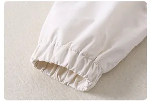 Gros plan des poignets élastiques sur veste coupe-vent enfant avec détails de couture