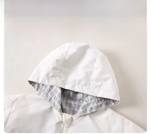 Detail of kids hooded jacket featuring a classic grey check lining and smooth resin zipper