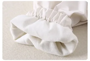 Détail des poignets élastiques sur veste enfant blanc cassé montrant la couture de qualité