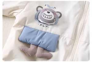 Detail of baby hooded jacket featuring 3D cartoon bear and FLY print on cream fabric