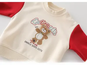 Detail of baby sweatshirt featuring shoulder buttons and 3D bear embroidery with text