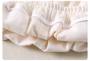 Dettaglio dell'elastico in vita con cuciture fini sui pantaloni crema da bambina
