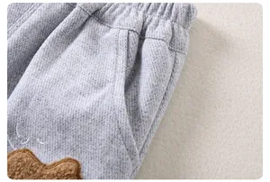Detail of elastic waist and plush bear patch on gray casual toddler trousers