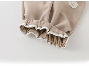 Detail of baby cotton pants showing precise stitching and soft beige knitted fabric texture