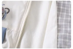 Detail view of child jacket showing white zipper, blue fabric panel, and plaid lining