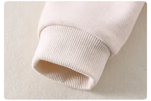 Detailed close-up of ribbed knit cuffs on a cream-colored toddler two-piece outfit